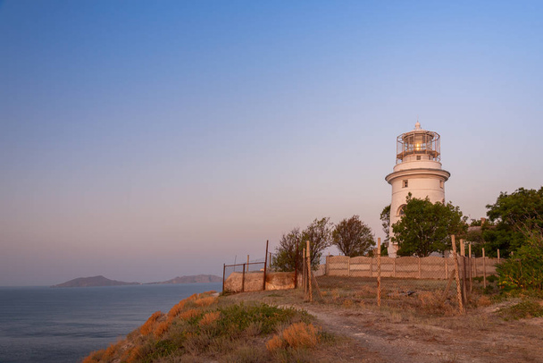 White sea lighthouse surrounded by green trees in Crimea on the Black Sea - Valokuva, kuva