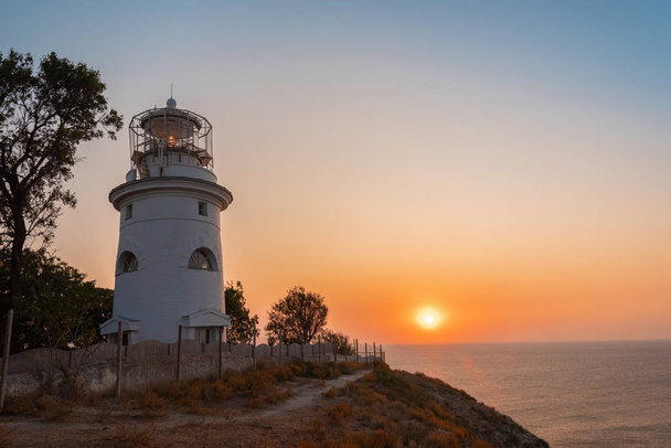 White sea lighthouse in Feodosia, Crimea on the Black Sea from sunrise - Foto, imagen