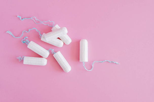 Several white sanitary tampons on a pink background. Menstrual mothly cycle, means of protection. Top view, flat lay, copy space for text. - Photo, Image