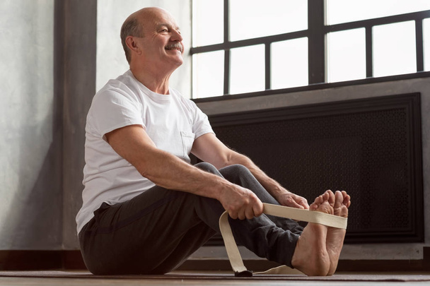 Senior Spaanse man zittend in Paschimottanasana of intense dorsale stretch pose - Foto, afbeelding