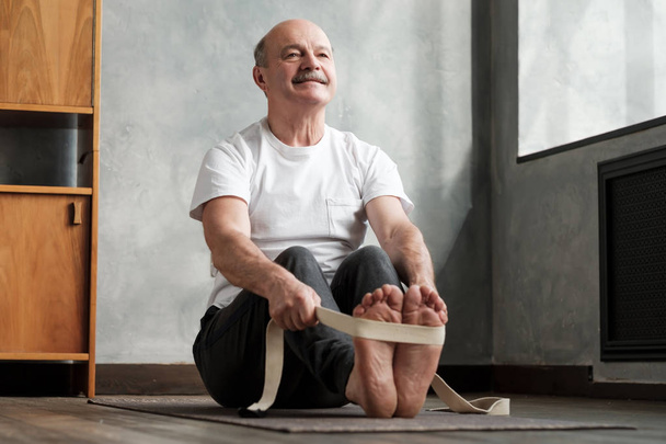 Homem hispânico sênior sentado em paschimottanasana ou intensa postura Dorsal Stretch
 - Foto, Imagem