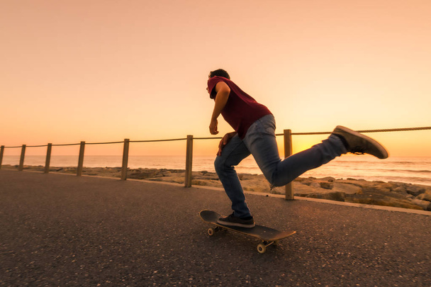 Skater training in the park near the sea in sunset. - Foto, afbeelding