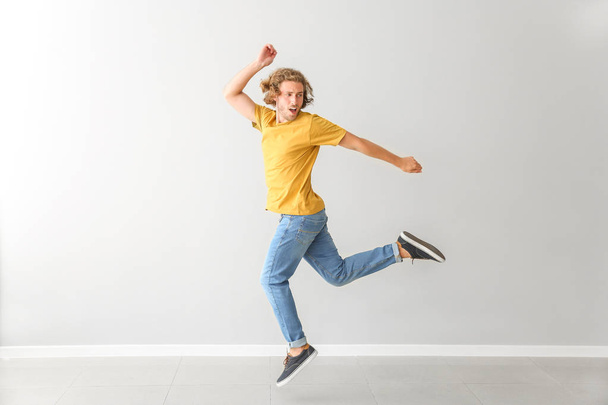 Handsome young man dancing against white wall - Photo, Image