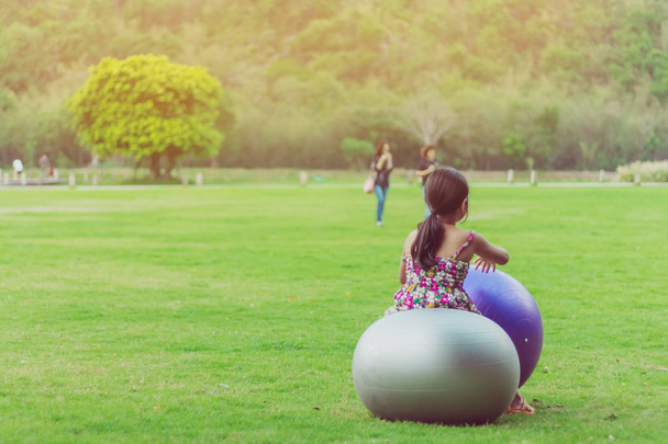 Çiçek etek Mutluluk kız dinlenmek ve kamu bahçesinde yeşil alanda büyük bir top ile oynamak. - Fotoğraf, Görsel