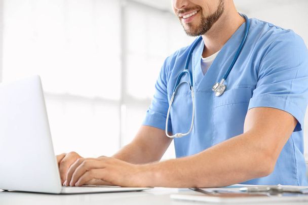 Male nurse working on laptop in clinic - Фото, зображення