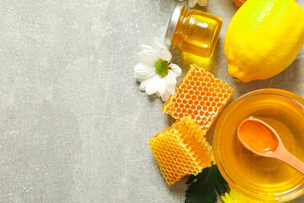 Επίπεδη με μέλι, λουλούδια και φρούτα σε γκρίζο φόντο, αντιγραφή - Φωτογραφία, εικόνα