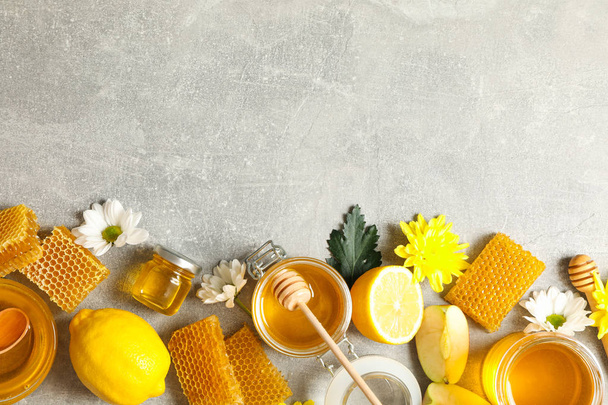 Platte lag met honing, bloemen en fruit op grijze achtergrond, kopiëren - Foto, afbeelding