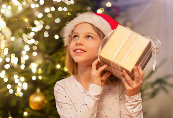 smiling girl in santa hat with christmas gift - Фото, зображення