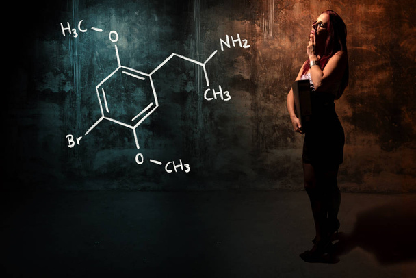 Seksowna dziewczyna lub Sekretarz lub studentka przedstawiająca ręcznie sporządzona formuła chemiczna Dimethoksybromoamfetaminy dob - Zdjęcie, obraz