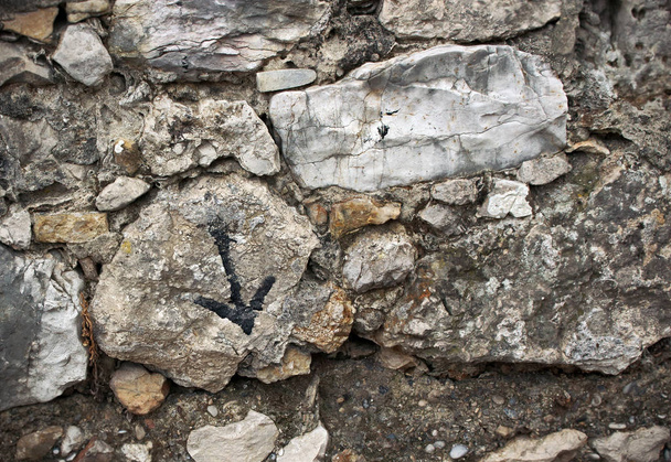 Aged old textured surface stone wall with painted arrow pointing down sign - Photo, Image