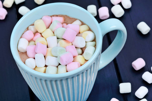 Hot chocolate with colorful marshmallows in a cup on a wood table - Foto, Imagen