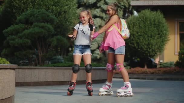 Baile divertido de dos chicas jóvenes patinando en un parque de la ciudad
 - Imágenes, Vídeo