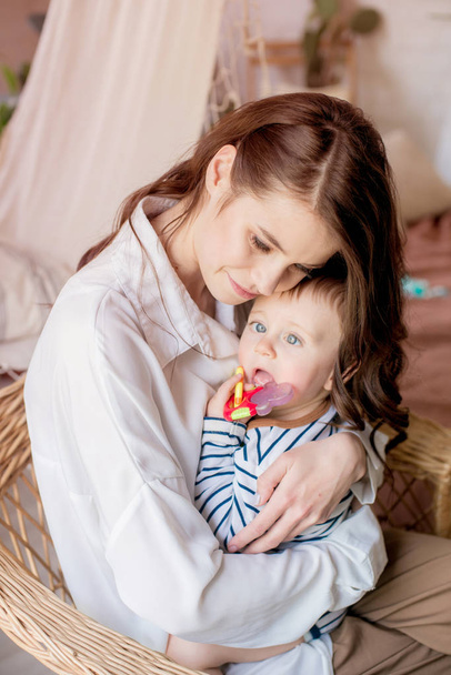 A young mother plays with her little son at home in the bedroom. Happy motherhood - Valokuva, kuva