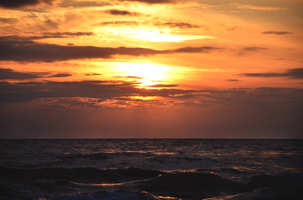 海岸の空オレンジ色のトーン雲と海の波美しい自然明るい夕日暗い水 - 写真・画像