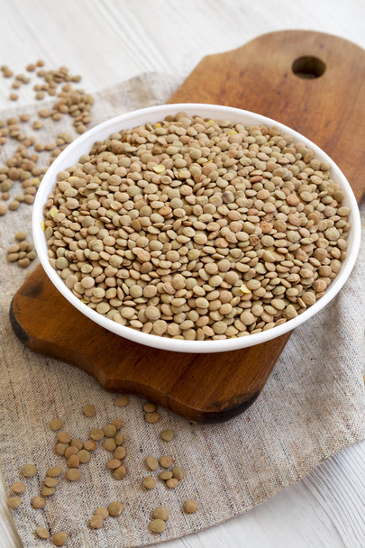 Organic green lentils in a white bowl on a rustic wooden board,  - Photo, Image