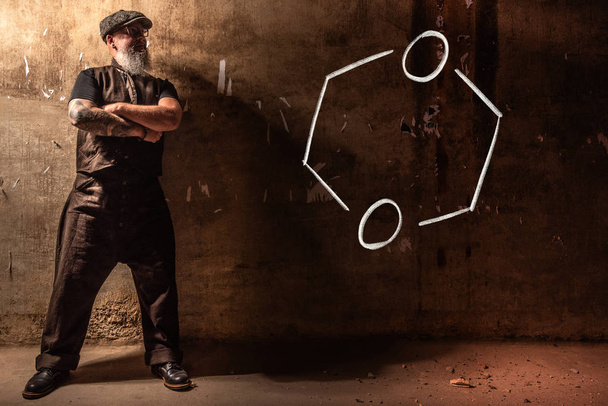Homem velho barbudo apresentando fórmula química desenhada à mão de Dioxano
 - Foto, Imagem