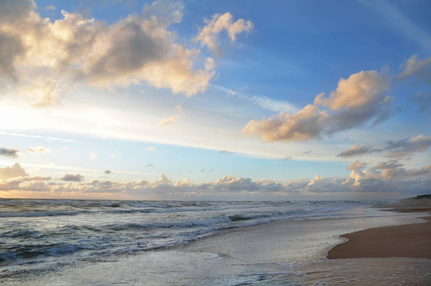 Seashore niebo pomarańczowy i niebieskie odcienie chmur i fale morskie piasek plaża z piękną przyrodą jasny zachód słońca - Zdjęcie, obraz