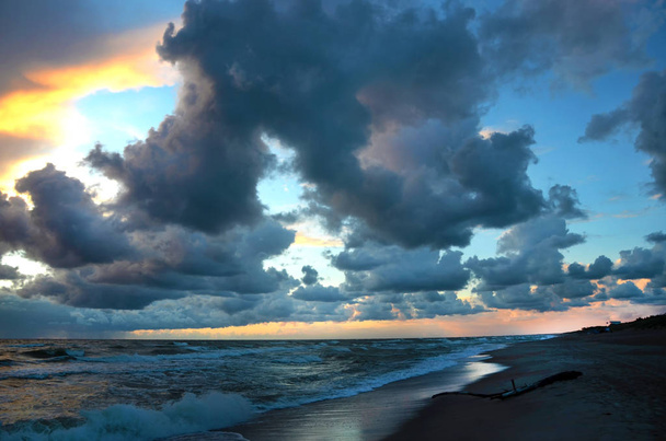 Seashore Sky oranje tinten zware wolken en zee golven mooie natuur Bright zonsondergang donker water - Foto, afbeelding