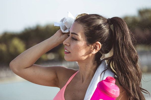 Bruna e attraente donna venezuelana, asciuga il sudore dalla fronte con un asciugamano dopo l'esercizio
. - Foto, immagini