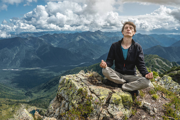 Homem caminhante sentado em uma pose de ioga no pico da montanha no verão. Meditação depois de uma longa subida em uma montanha
 - Foto, Imagem