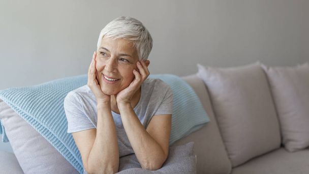 Happy mature woman sitting posing on couch.  - Фото, изображение