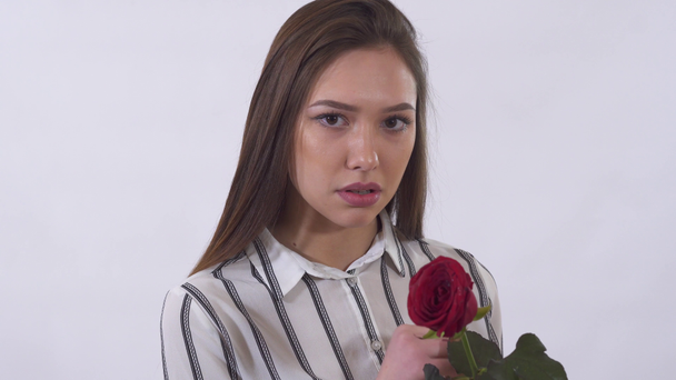 unglückliche junge schöne Frau ist sehr traurig, wenn sie Blütenblätter aus der roten erstaunlichen Rose zieht. - Filmmaterial, Video