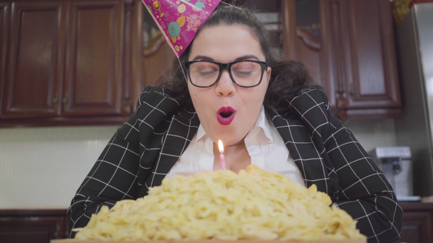 脂肪幸せな女の子でお祝いの帽子とスタイリッシュな眼鏡でザ · テーブルの上にキッチンと吹いてキャンドル,ビデオ  - 映像、動画