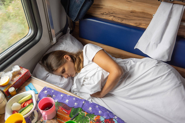 Nuori tyttö nukkuu punkassa junassa.
 - Valokuva, kuva