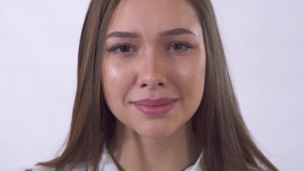 Portrait of sad young woman, crying close up in studio. Tear runs down cheek. Lady is depressed, disappointed her face shows grief. Shooting in the studio on a white background - Metraje, vídeo