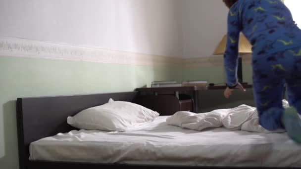 Small cute adorable boy running inside the bedroom and jumping fast in bed pretend like he is sleeping. - Filmati, video