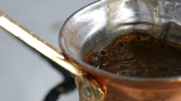 Őrölt fekete kávét a réz Turk főzik, és kelések egy gáztűzhely. Barista előkészítése forró ízletes ital otthon közelről - Felvétel, videó