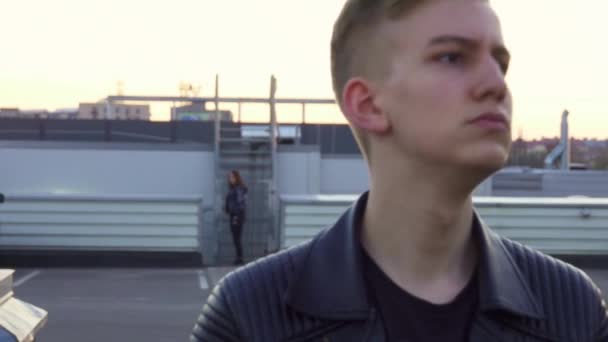 Cute young male with nice blond haircut in jacket stands outside and smiles. - Filmati, video