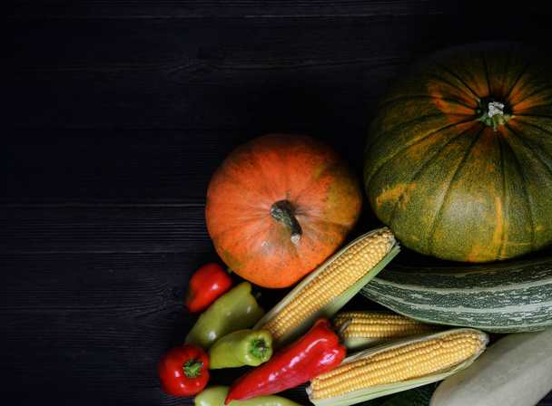 Осенний овощной фон с тёмным деревянным столом. День благодарения урожая. Поздравительная открытка, плакат, концепция баннера с копировальным пространством для текста. Органические вегетарианские продукты тыква, кукуруза, капуста, перец
 - Фото, изображение