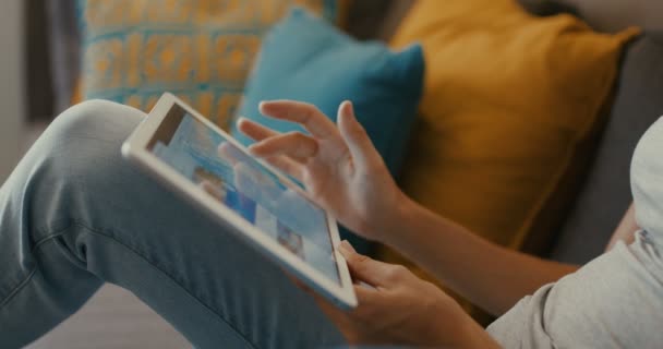 Imágenes de alta calidad de 4k 12bit de Beautiful girl usando Tablet PC sentado en el sofá en casa. Mujer navegando por la web, redes sociales, buscando algo en la tienda en línea. Aspecto cinematográfico
 - Imágenes, Vídeo