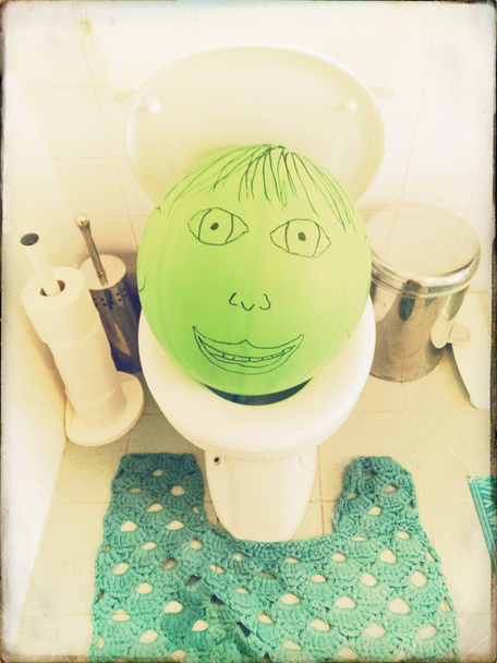 globo verde con la cara pintada en un inodoro
 - Foto, Imagen