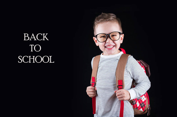 黒い背景に陽気な笑顔の小さな男の子。カメラを見て学校のコンセプト - 写真・画像