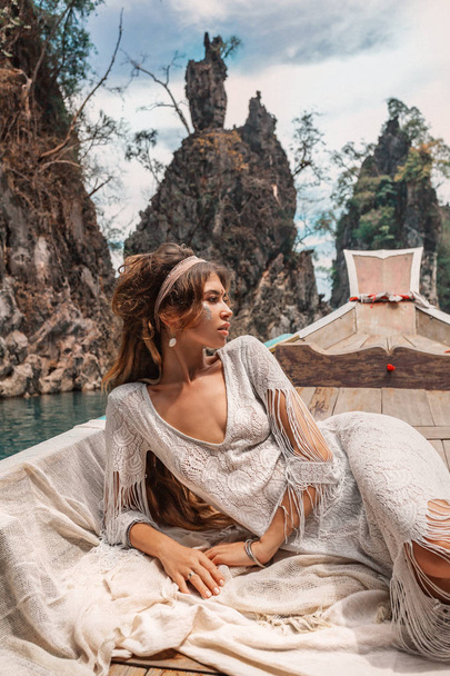 fashionable young model in boho style dress lying on boat  - Photo, image