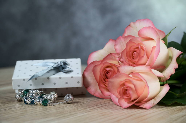 τριαντάφυλλα Dolce Vita με διακεκομμένο λευκό παρόν κουτί σε φόντο ξύλου - Φωτογραφία, εικόνα