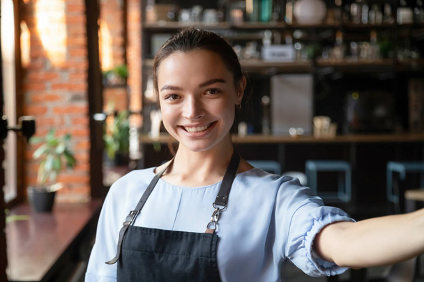 Kopfschuss Porträt der attraktiven lächelnden Kellnerin im gemütlichen Kaffeehaus - Foto, Bild