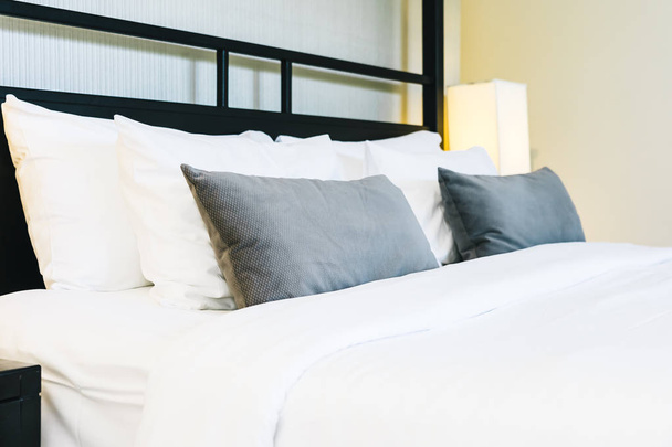 Mooie luxe comfortabele kussen op bed met licht lamp - Foto, afbeelding