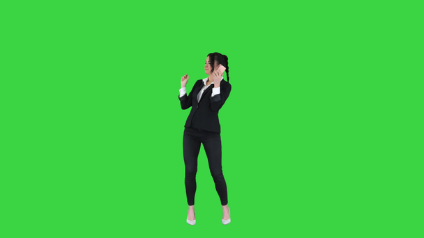 Joven mujer de negocios escuchando música en el teléfono y bailando en una pantalla verde, Chroma Key. - Metraje, vídeo