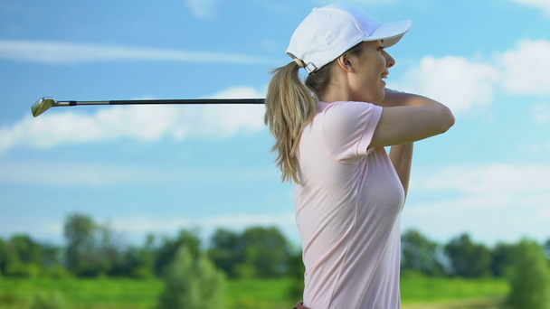 junge Frau beim Golftraining auf dem Platz bei sonnigem Tag, glücklich über guten Schlag - Filmmaterial, Video