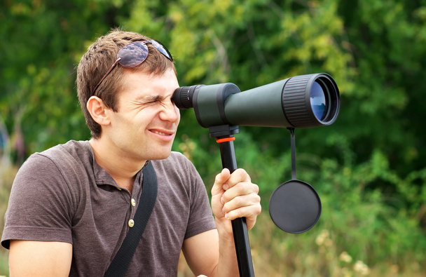 Man who is watching in spotting scope. Positive man looking thro - 写真・画像