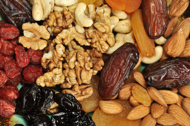 The whole space of the frame is occupied by dried fruits and nuts. In the frame there are dried apricots, prunes, almonds, cashews, raisins, cherries, walnuts, dates. View from above. Close-up. Macro - Foto, imagen