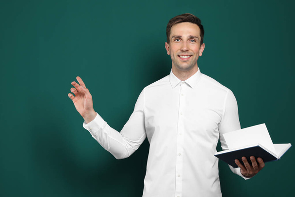 Portrait of male teacher with book on color background - Foto, afbeelding
