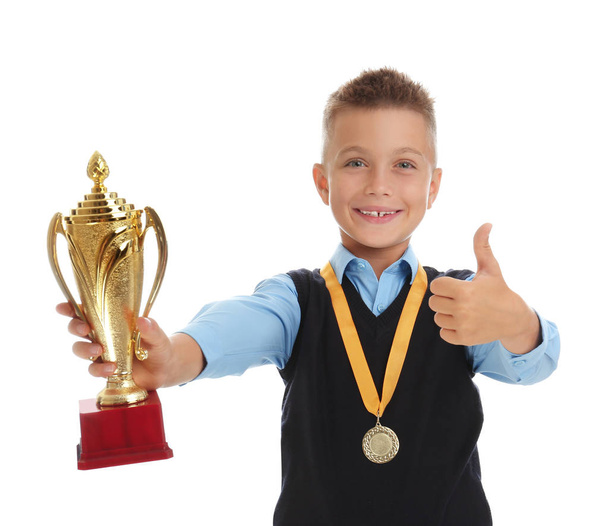 Happy boy in school uniform with golden winning cup and medal isolated on white - Foto, Imagem