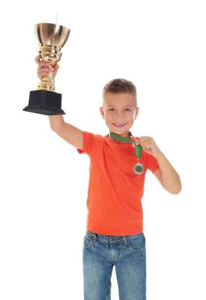 Happy boy with golden winning cup and medal isolated on white - Фото, изображение