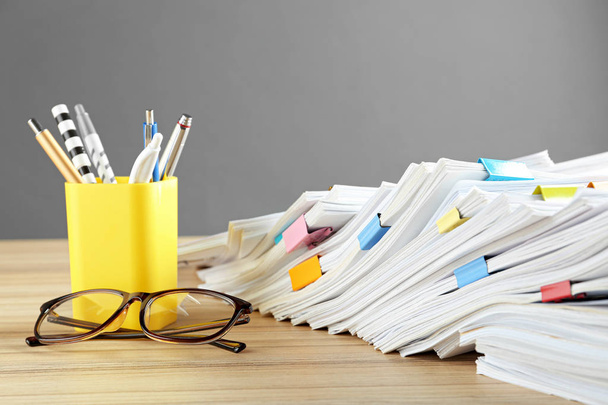 Stack of documents with binder clips and glasses on wooden table - Фото, изображение