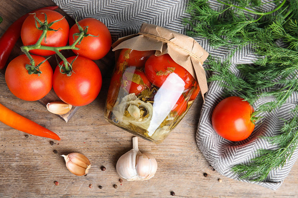 Flat lay composition with pickled tomatoes in glass jar on wooden table - Fotografie, Obrázek