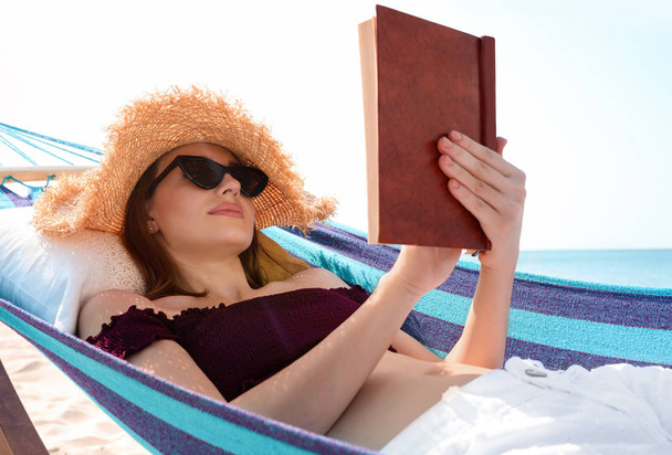 Young woman reading book in hammock on beach - Photo, image